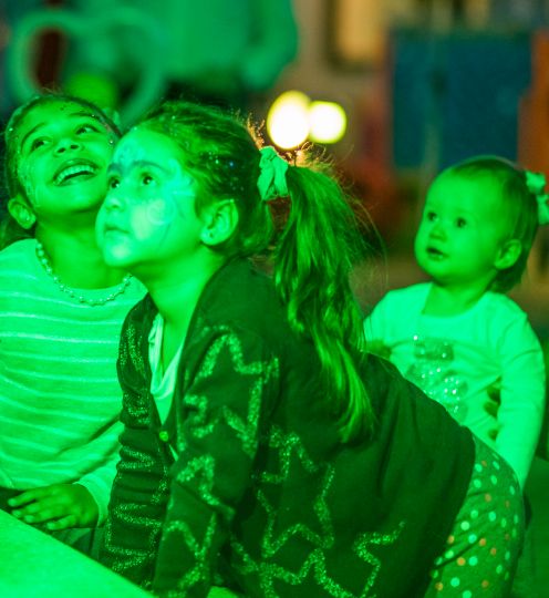 children bathed in green light look off to the side