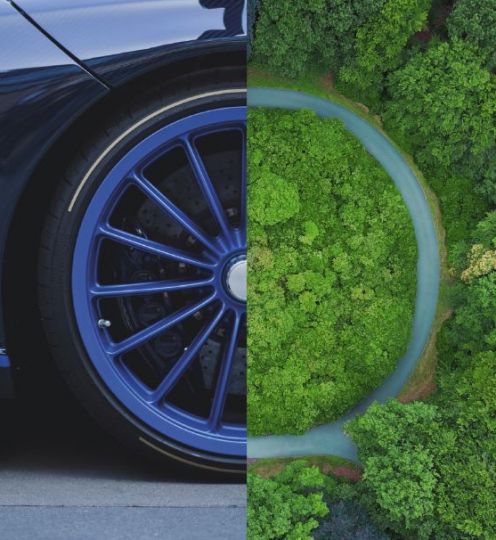 black car with blue trimmed wheel fades into circular path through green wooded area