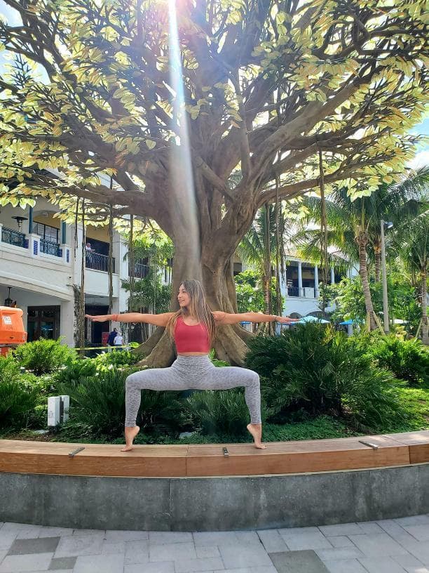 Women striking yoga pose in front of The Wishing Tree 