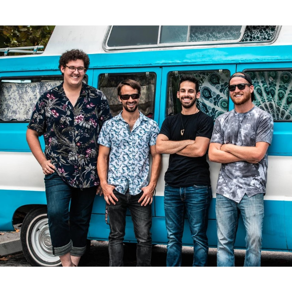 four men stand in front of blue and white vehicle
