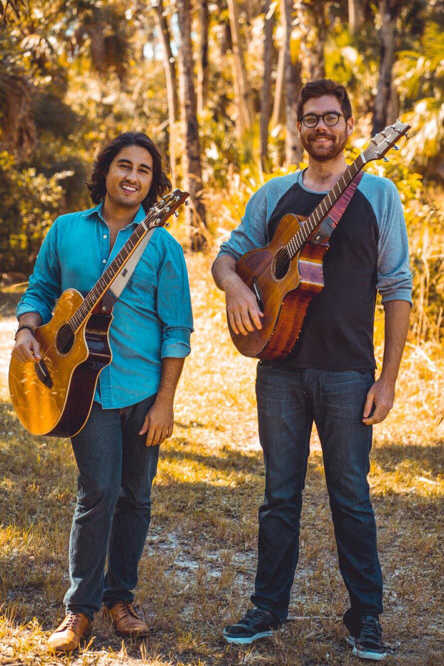 Two musicians holding their guitars
