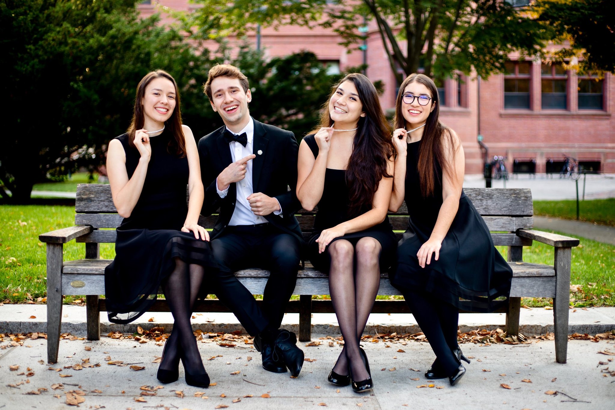 A four piece a cappella singing group sitting on a bench