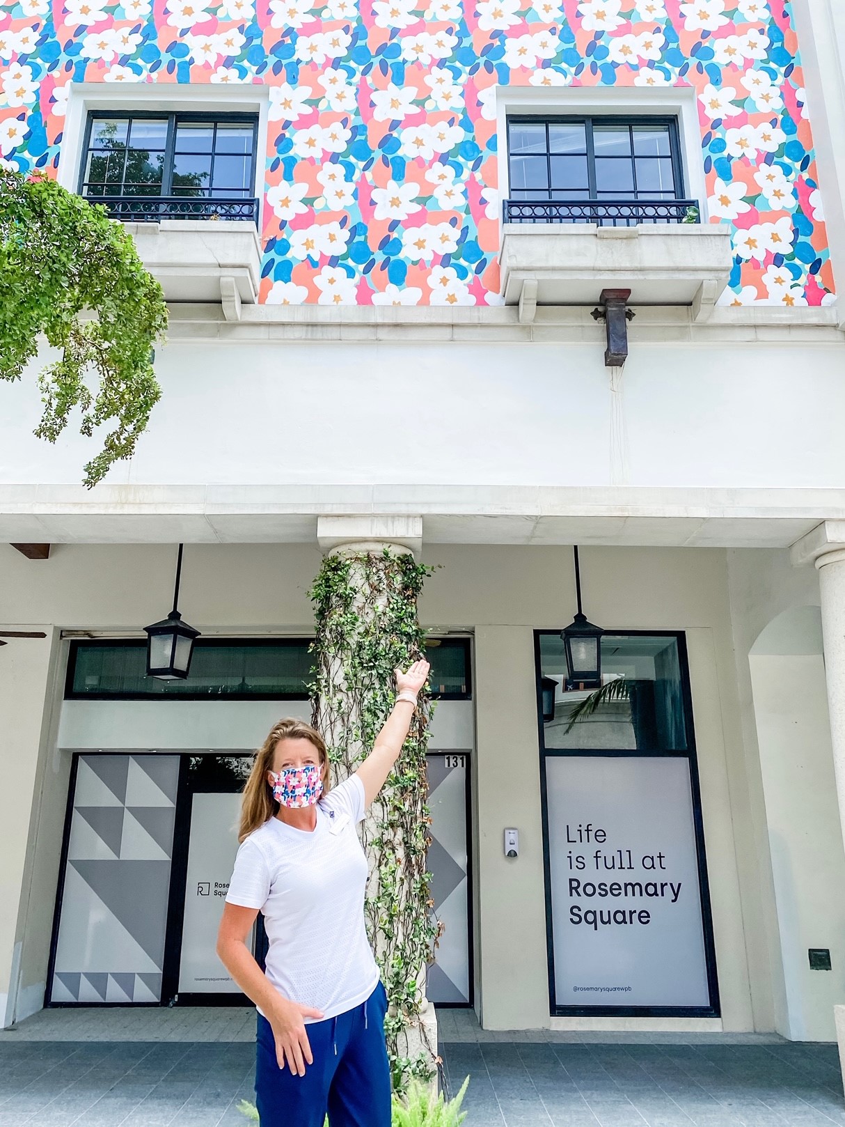 women in floral mask that is same design as building floral mural