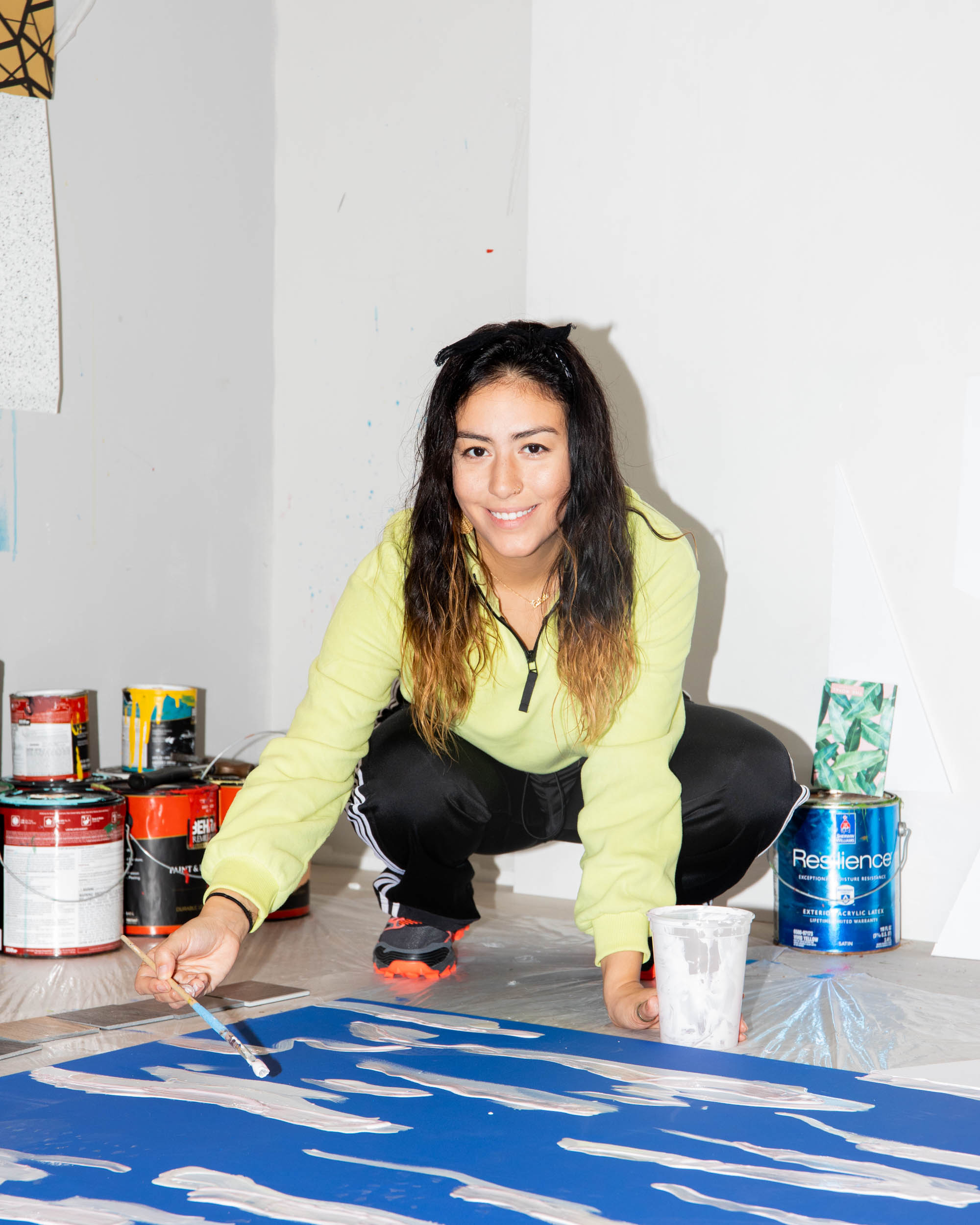 Artist crouching while painting canvas on the floor