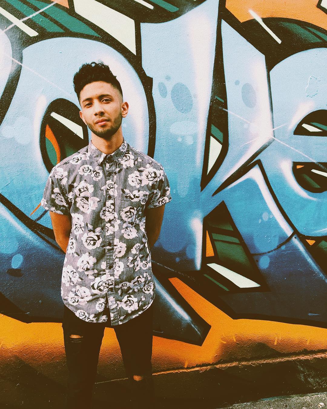 Young man standing in front of artistic mural