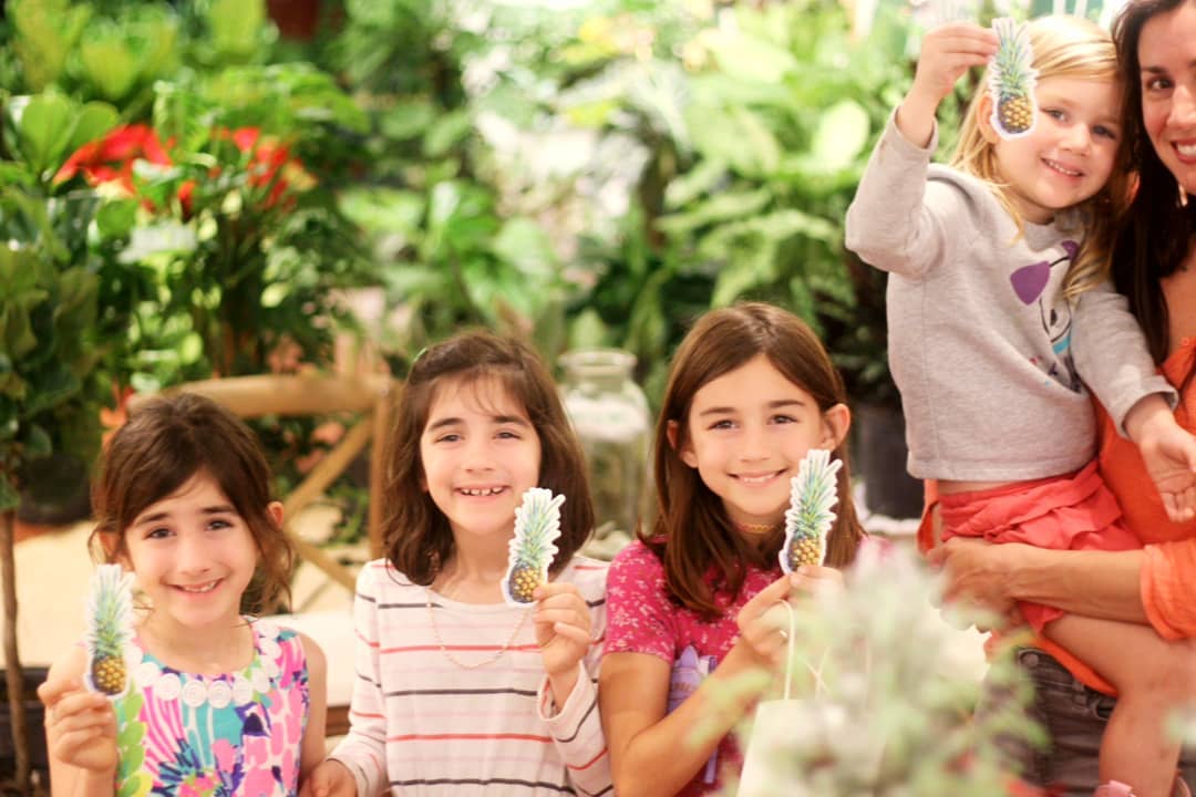 Three children smiling holding up a pineapple sticker