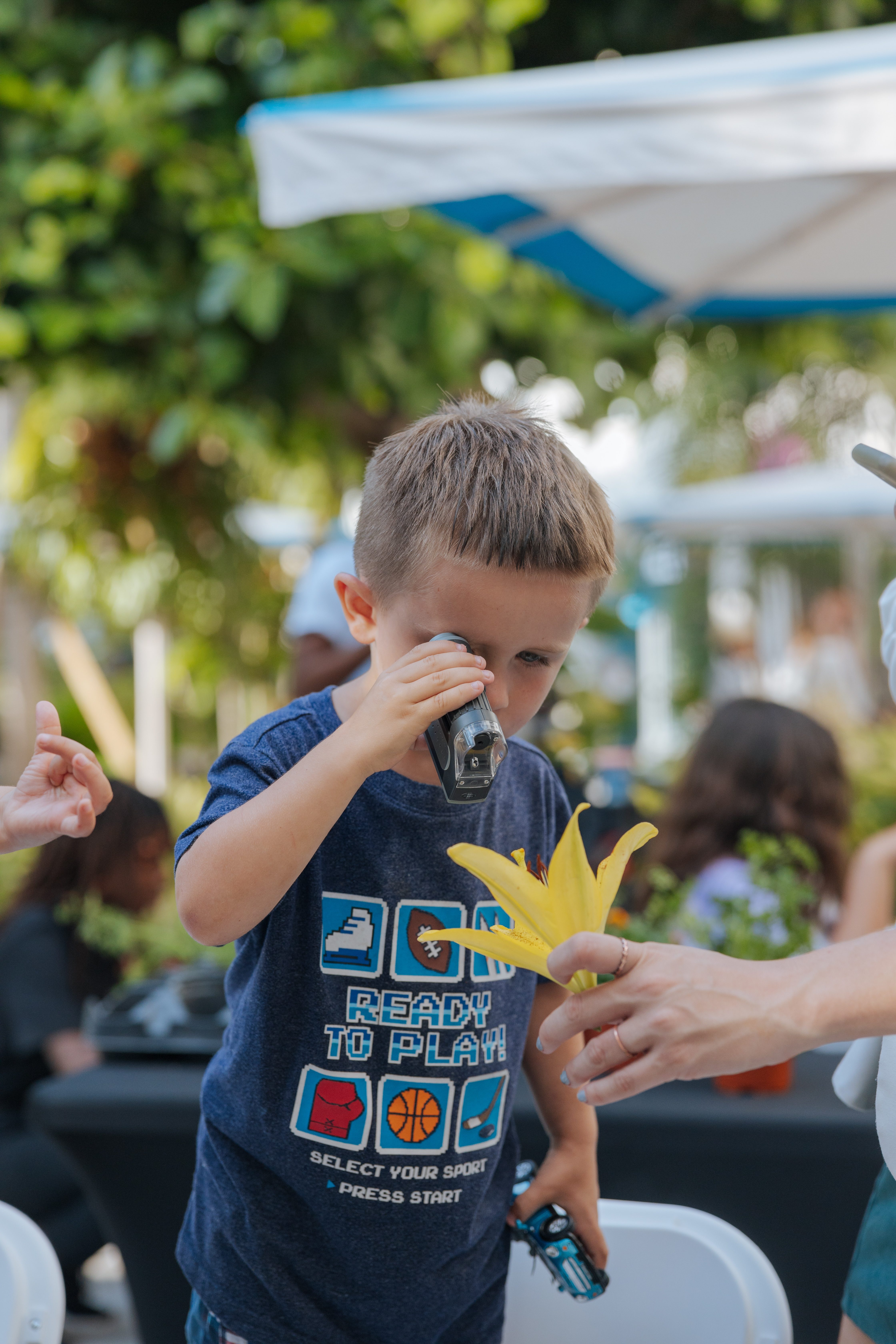 Little boy looking at flower through magnifying glass 