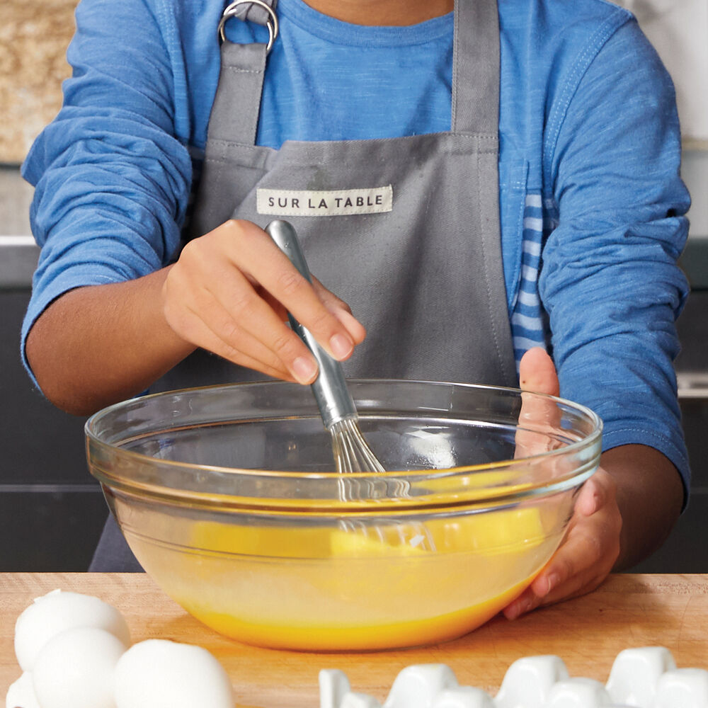 a kid in the kitchen whisking eggs