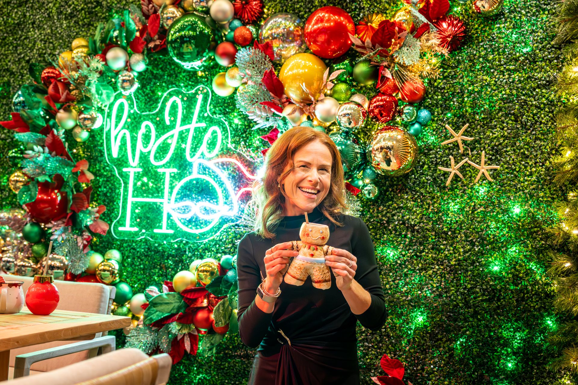 Woman smiling while holiday a drink in a gingerbread mug