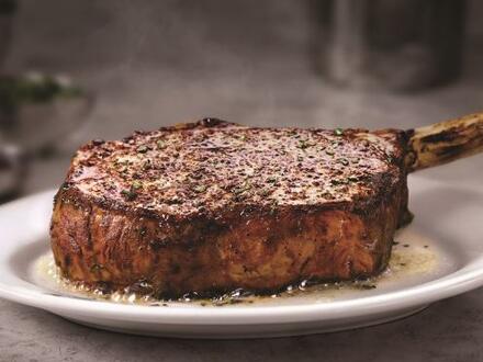 bone-in steak sitting on circular white plate