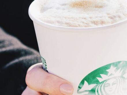 person holding a to-go beverage from Starbucks
