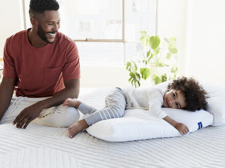 Father and young son sitting on bed