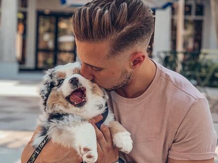 Young man giving puppy a kiss
