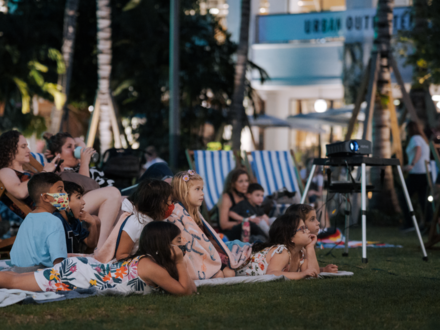 Little kids laying on a lawn watching an outdoor movie 