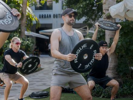 Man holding a weight in his hands while doing a workout on the lawn