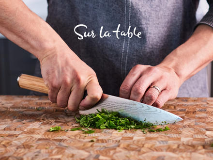 Man cutting green onion with a Sur La Table apron on