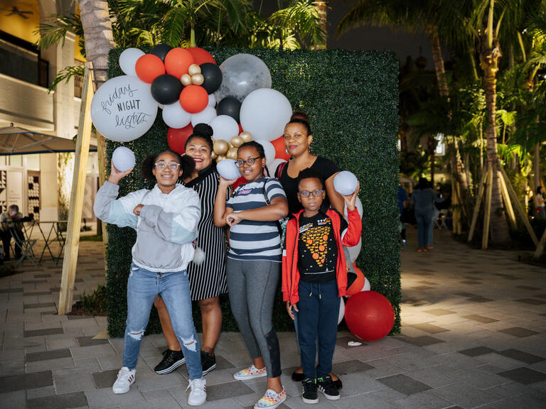 Family of five posing in front of balloons with footballs in hand