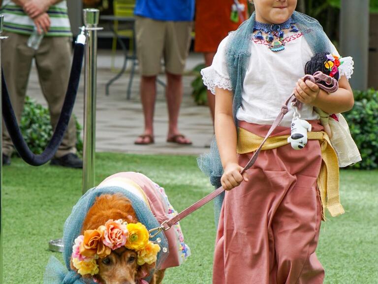Girl in a costume walking a dog in a costume