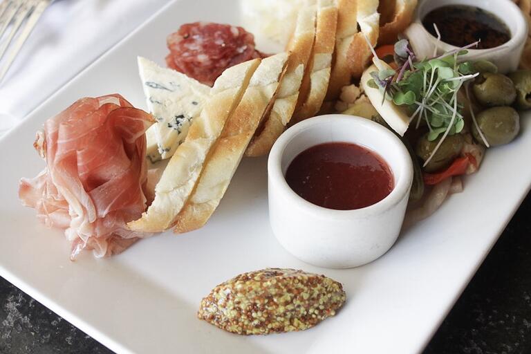 assortment of dips, cheese, and bread on white plate