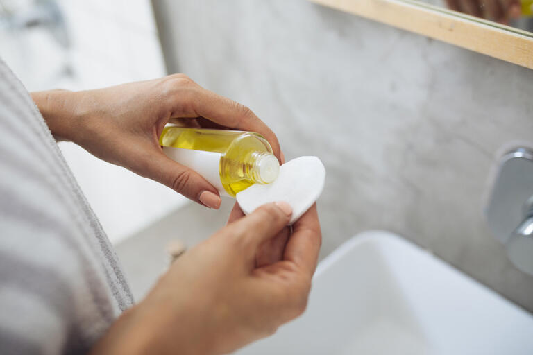 Woman pouring beauty product on cotton pad