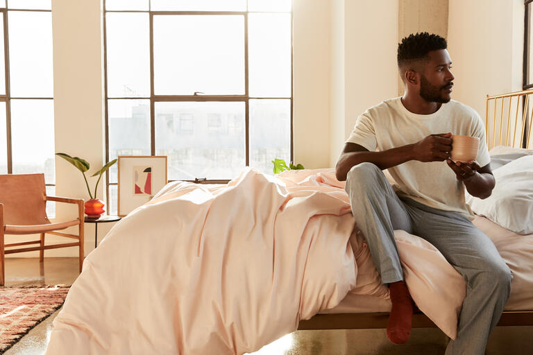 Man sitting on bed with coffee