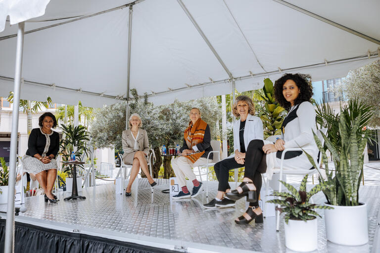 Five women sitting no stage smiling 