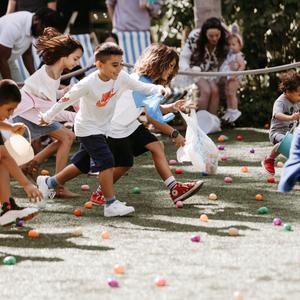 Kids running on a lawn towards plastic easter eggs